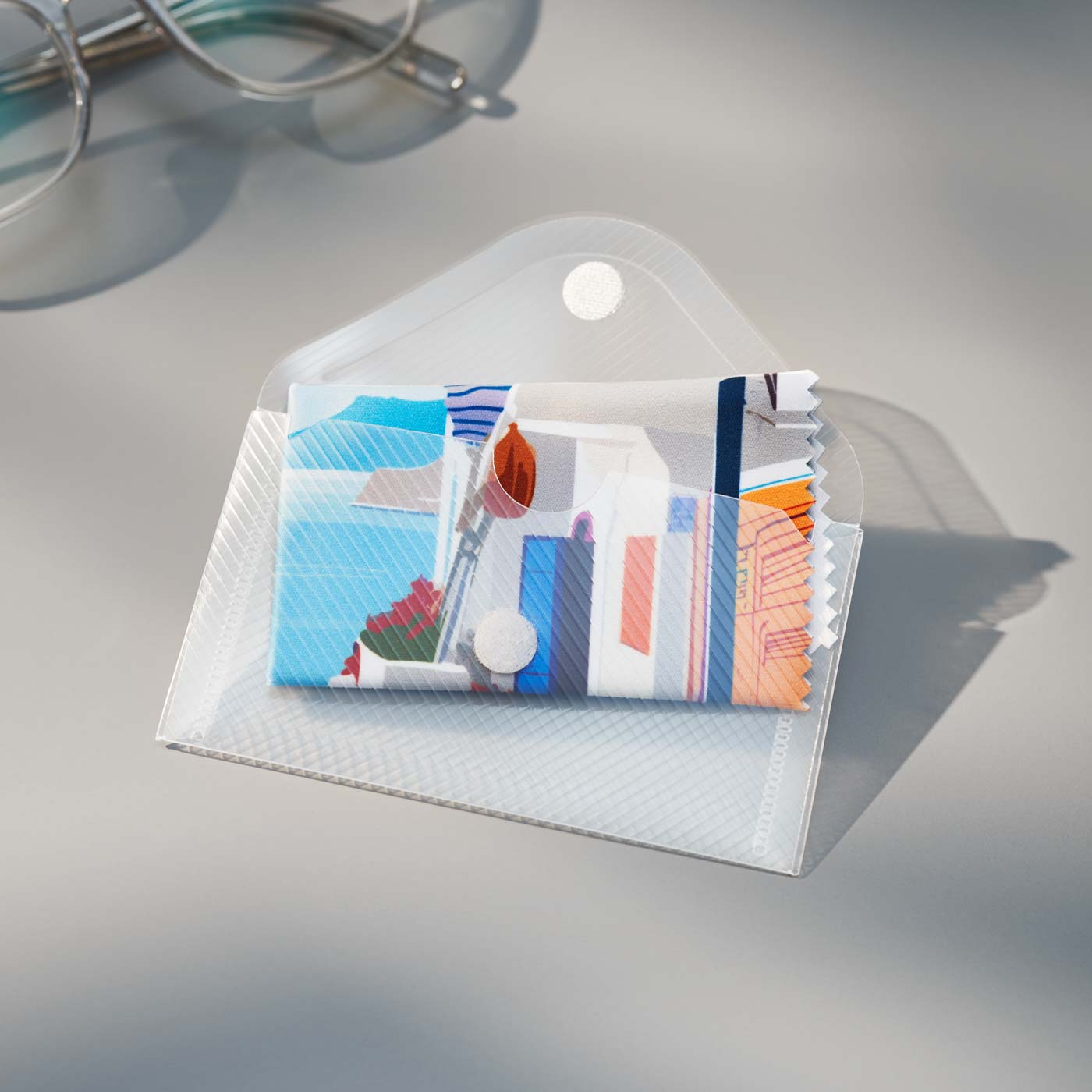 Ein farbenfrohes, individuelles Mikrofaser-Reinigungstuch mit mediterranem Landschaftsdruck in einer durchsichtigen Plastikhülle.